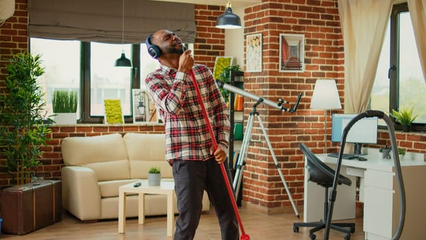 African american person using mop to wash wooden floors