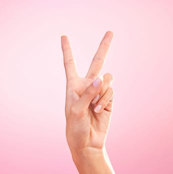 Woman, hands and peace sign, emoji or symbol for freedom against a pink studio background. Hand of female showing peaceful V icon or shape for hope, support or trust in vote or voice on mockup