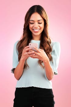 Phone, texting and happy woman in studio online for communication, social media or app on pink background. Internet, smartphone and girl smile with streaming, subscription or website search isolated