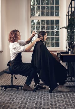 Blessed are the hairstylists, for they bring out the beauty in others. a young woman getting her hair cut in a salon.