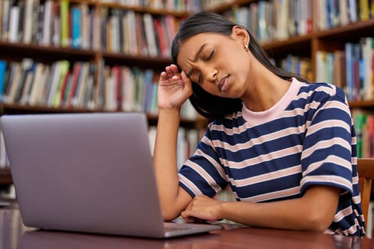 Study while others are sleeping. a hispanic female using a laptop and being stressed in a library.
