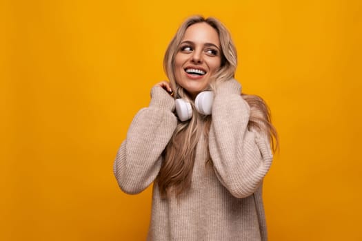 cute lady with headphones around her neck smiling on a yellow background
