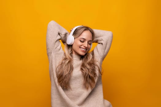girl attentively listens to a podcast in headphones on a yellow background
