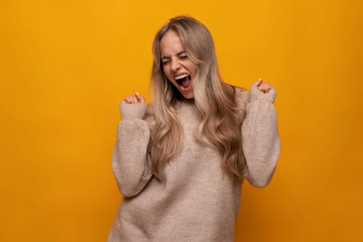 caucasian young woman emotionally rejoices among yellow background