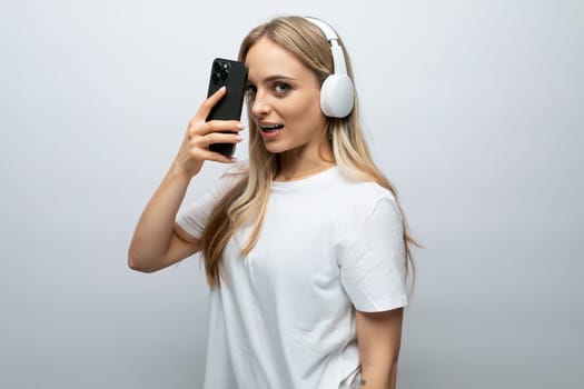 blogger girl with a headset on her head and a phone in her hands on a white background