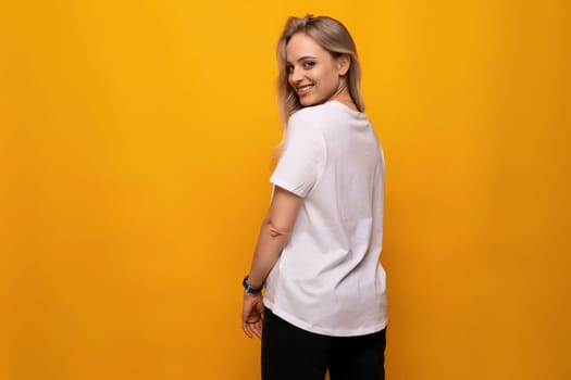 shy blond girl in a white T-shirt on a yellow background