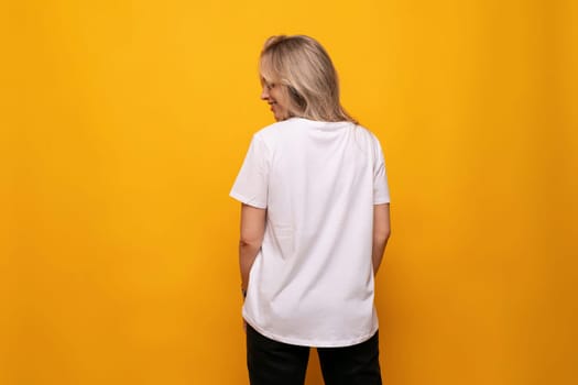a girl with a mockup of a white T-shirt stands with her back on a yellow background