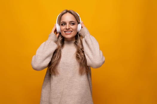 young woman listens to music and sings along with headphones on a yellow background