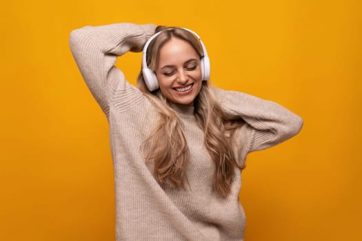 joyful european young woman enjoying meditation with headphones on yellow background