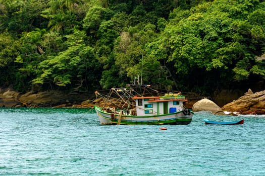 Fishing trawler anchored along the rocks and forest