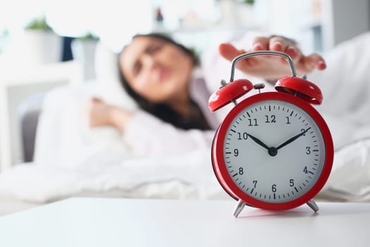 Dissatisfied woman turns off the alarm clock in bed