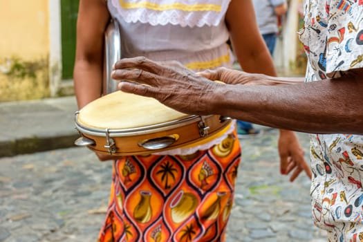 Tambourine player with a woman in typical clothes dancing in the background