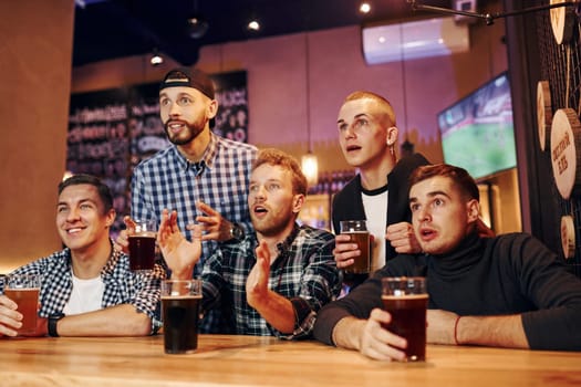 Football fans watching TV. Group of people together indoors in the pub have fun at weekend time