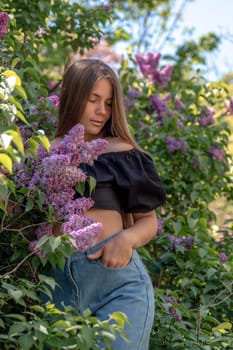 portrait of young woman with long hair outdoors in blooming lilac garden