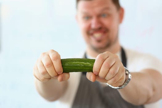 Emotional male cook with cucumber vegetable in hand