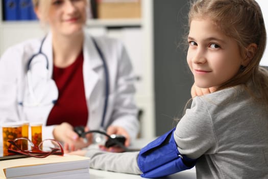 Doctor measures blood pressure of little girl child