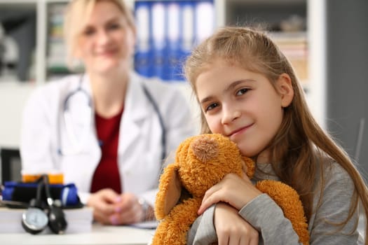 Little girl holding bear toy at medical appointment with pediatrician