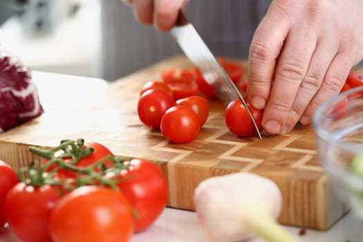 Chef cuts fresh ripe tomatoes on cutting board