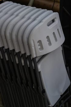 Plastic folding chairs are white stacked on top