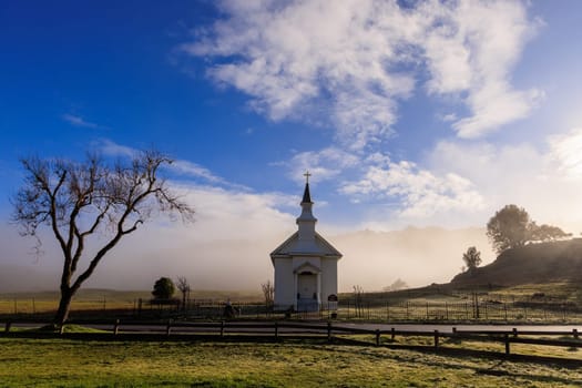 Low fog behind small rural church in Marin County, California at sunrise