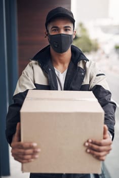 Delivering your goods safe and without delay. a masked young man delivering a package to a place of residence.