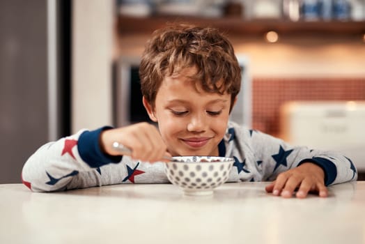 Ill be ready for anything after breakfast. a young boy eating cereal at home.