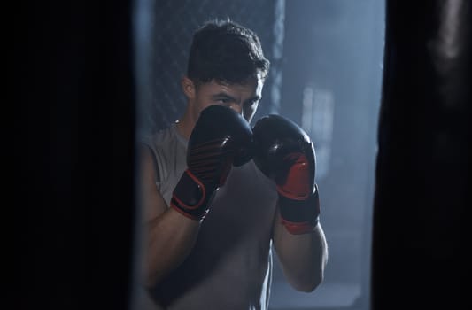 Strong is an attitude. a young man practicing his boxing routine at a gym.