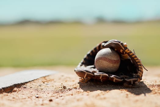 Step up to the plate. a baseball mitt and ball lying on the pitch during the day.