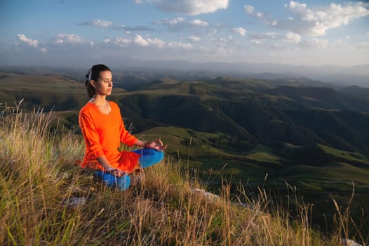Attractive woman doing yoga. Healthy lifestyle. Woman doing yoga in the mountains. Girl doing yoga at sunrise. Woman meditates in nature. Meditation in the mountains.