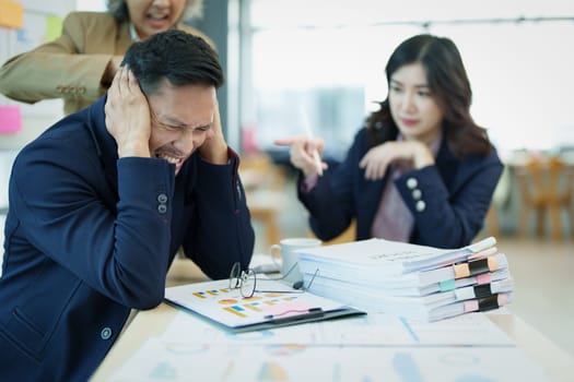 An image of an Asian male employee looking worried and sad about being scolded by his boss for failing to meet sales targets, concept of disappointment and failure in his career