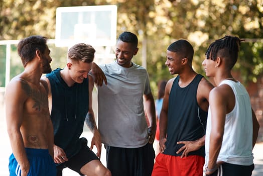 They always gather around after a game. a group of sporty young men standing on a basketball court.