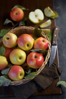 Ripe apples in a basket, with leaves around it