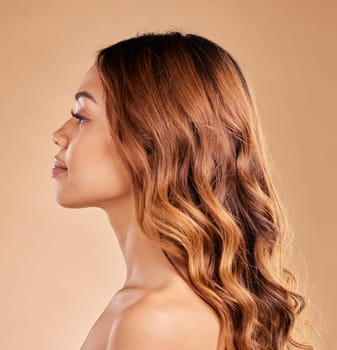 Woman, beauty and hair care profile with healthy growth or shine and strong texture on brown background. Aesthetic female in studio with glow, long curls and color for haircare and skincare wellness