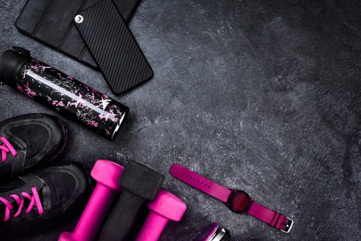 Am I missing something. High angle shot of a group of workout essentials lying on top of a dark background inside of a studio.