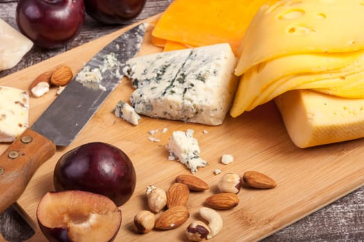Cheese, nuts and fruits on wooden background