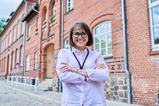 Portrait of female teacher, facade of educational building background