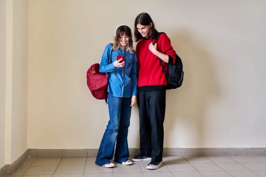 Teenage boy and girl looking at smartphone together.