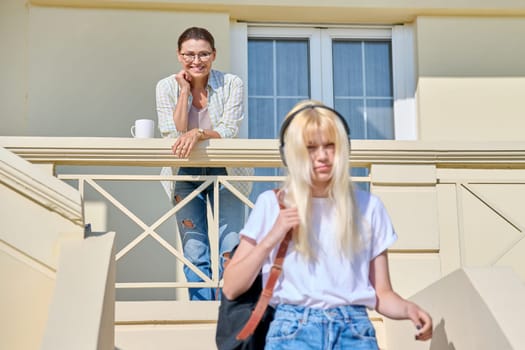 Middle-aged mother seeing off her teenage daughter on the porch of the house