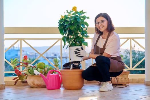 Woman planting caring for a house plant in a pot, on the terrace