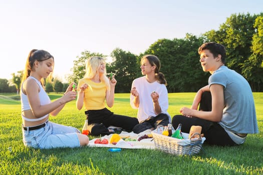 Teenagers having fun on a picnic in the park on lawn