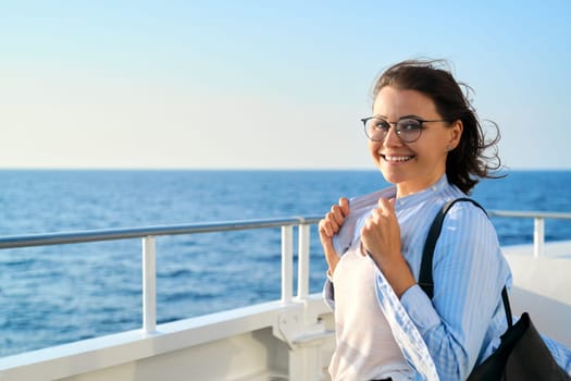 Happy middle aged woman on deck of cruise ship, copy space