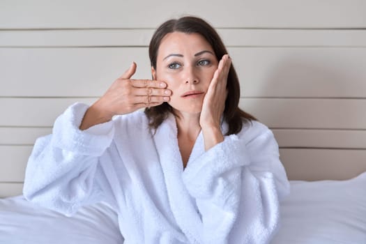 Middle age woman doing face massage, age beauty and facial skin care