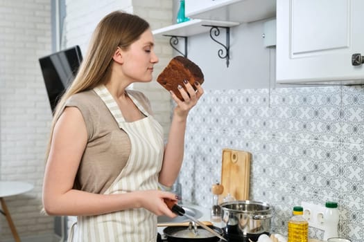 Young woman enjoying the smell of dark rye bread at home in the kitchen