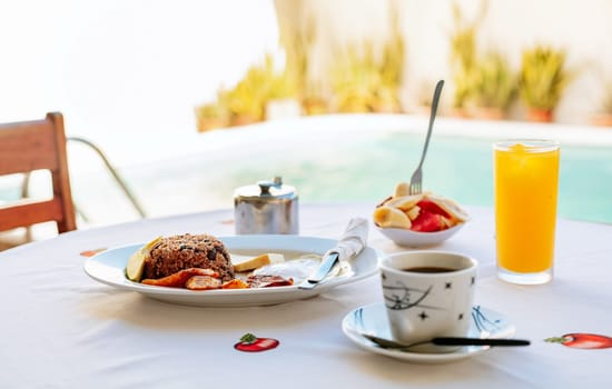 Close-up of a traditional breakfast on a table with a swimming pool in the background. Morning breakfast on the table near a swimming pool