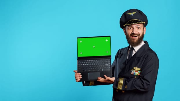 Happy young pilot holding laptop with greenscreen