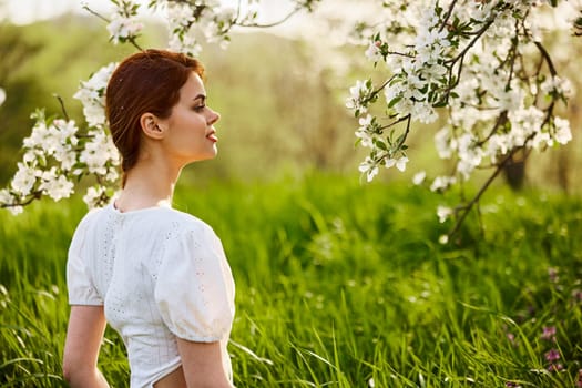 portrait of a beautiful woman looking at the flowers of an apple tree