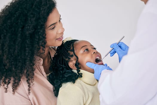 Children, mother and a girl at the dentist for oral hygiene or a checkup to search for a cavity or gum disease. Kids, dental or healthcare with a female child and mother at the orthodontist.