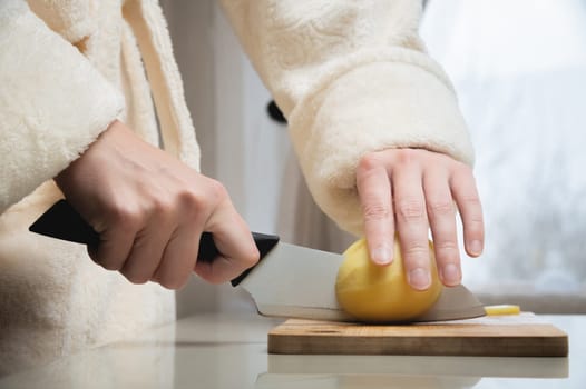 housewife cuts raw potatoes into small pieces with a knife. Close-up of hands while working in the kitchen. Cooking delicious breakfast or dinner