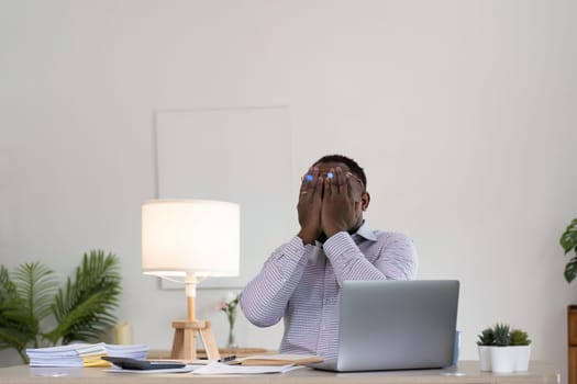 Unhappy black male worker at laptop screen shocked by gadget breakdown or operational problems. Frustrated man confused surprised by unexpected error on computer device