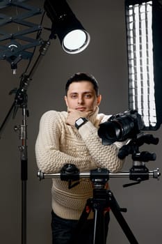 Professional handsome photographer with digital camera on tripod